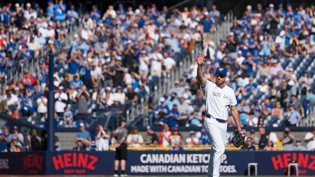 A baseball player in a Toronto Blue Jays uniform waves to the crowd during a game.