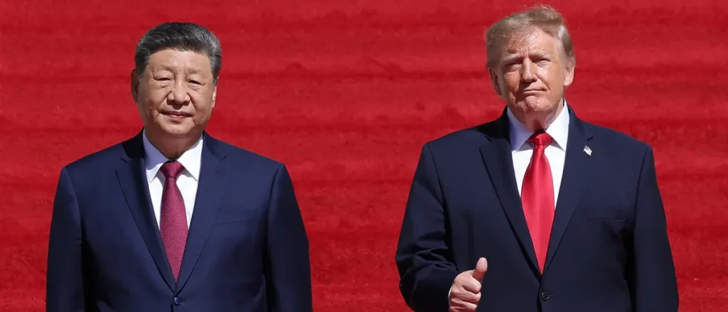 The photo shows two individuals in formal attire standing side by side against a red background.