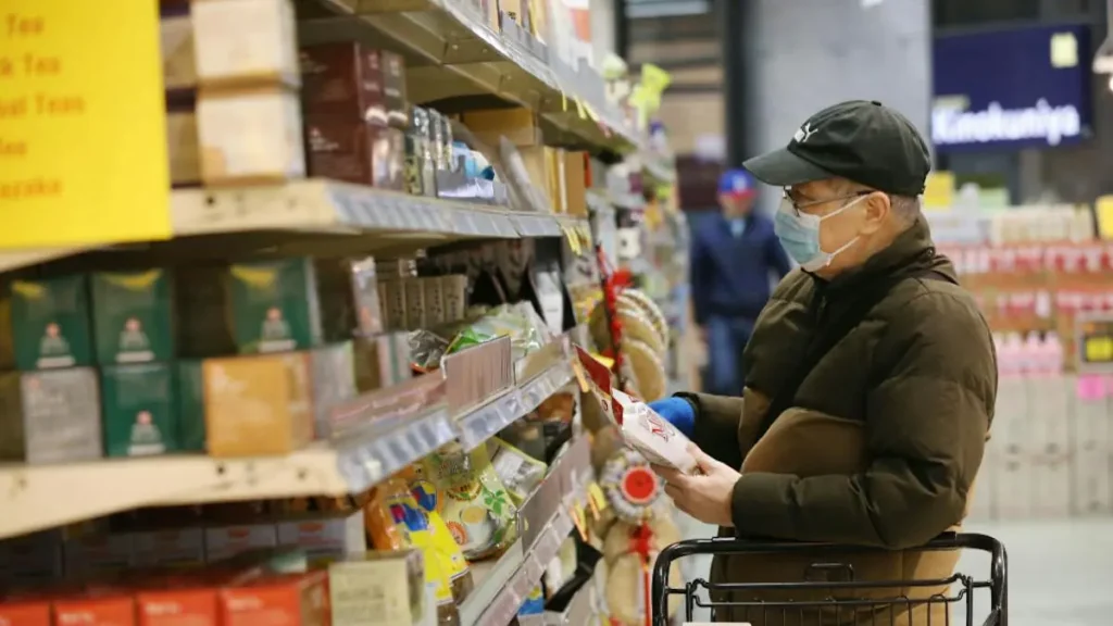 A person wearing a mask and gloves shops in a grocery store aisle.