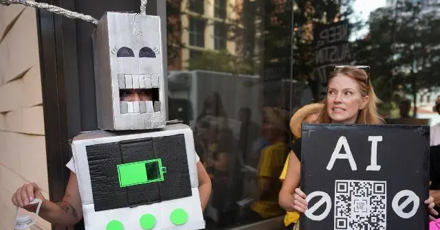 A person dressed as a robot holds a sign with a QR code and symbols, while another person stands nearby holding a sign that reads "AI."