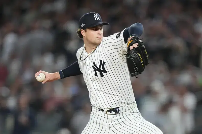 A baseball pitcher in a New York Yankees uniform is captured mid-pitch during a game.