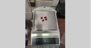 The image shows a digital scale with four red objects placed on its platform, likely in a legal or forensic context.