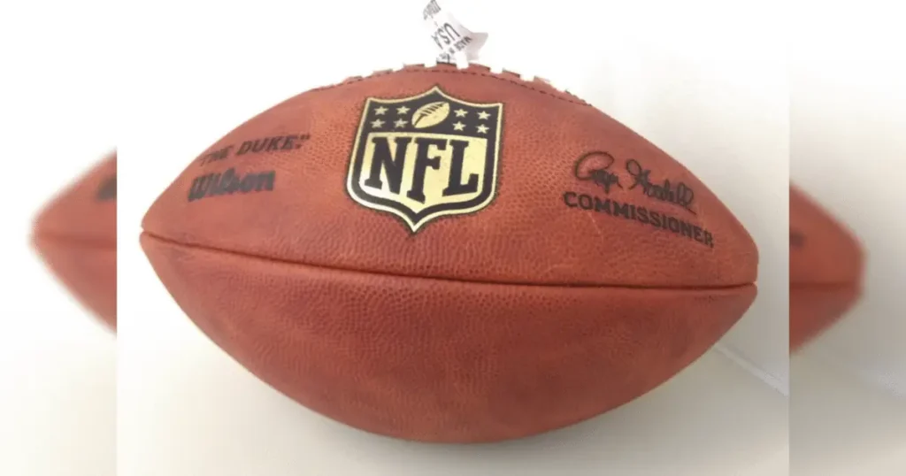The image shows a close-up of an NFL football with the NFL logo and "The Duke" branding.