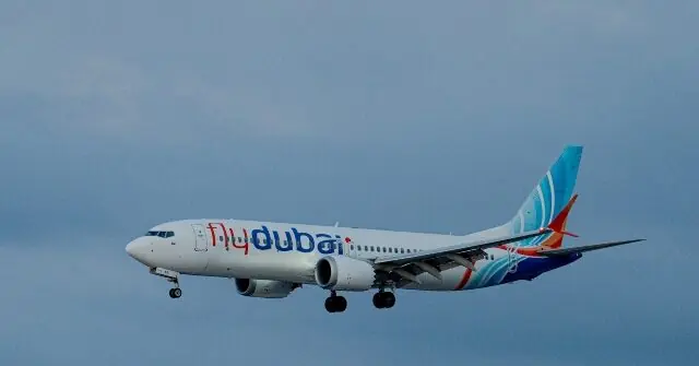 A flydubai aircraft is captured in flight against a clear sky.