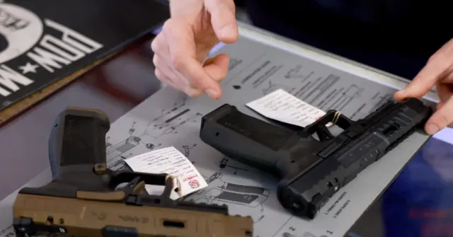 The image shows a close-up of a person's hands handling a disassembled handgun on a table with diagrams and instructions.