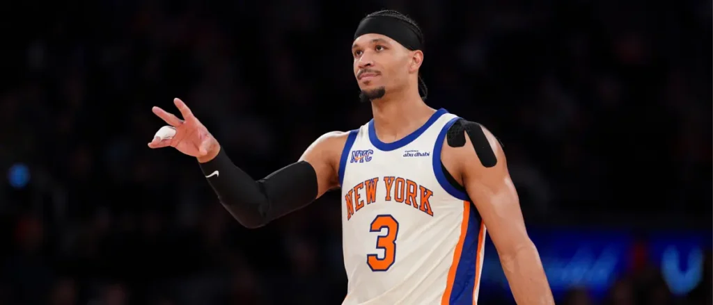 The image shows a basketball player wearing a New York Knicks jersey, number 3, with a black headband and a black arm sleeve, gesturing with his hand.