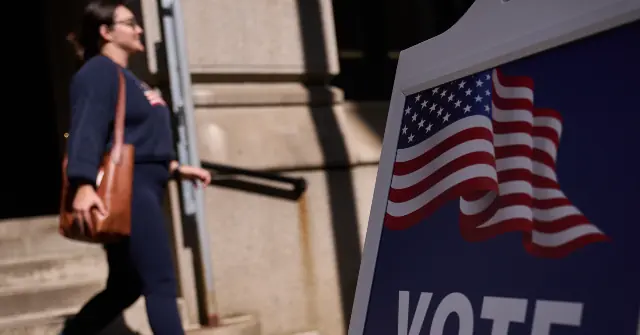 A person walks past a "VOTE" sign with an American flag, symbolizing civic engagement and the democratic process.