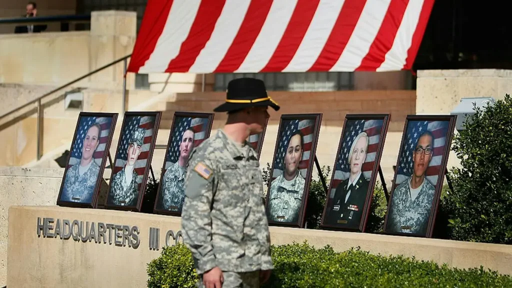 A soldier salutes portraits of fallen service members displayed in front of a U.S. flag at the Headquarters III Corps.