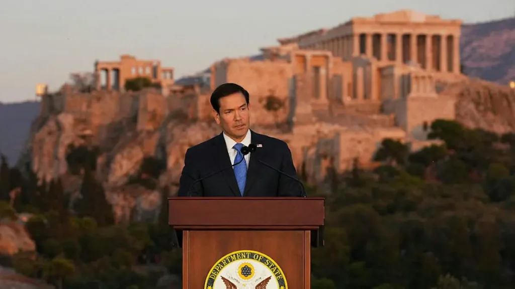 A man stands at a podium with the Department of State seal, delivering a speech in front of the Acropolis in Athens, Greece.