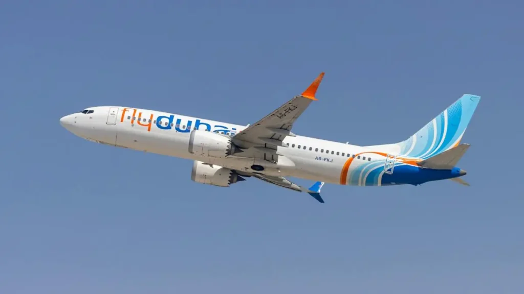 A flydubai aircraft is captured in flight against a clear blue sky.