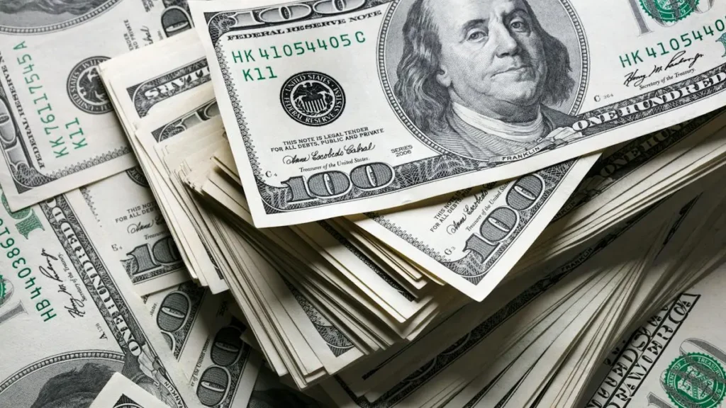 The image shows a pile of one hundred-dollar bills, symbolizing wealth or financial transactions.