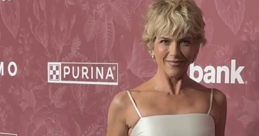 The image shows a person in a white dress standing in front of a backdrop featuring the Purina logo and other text.