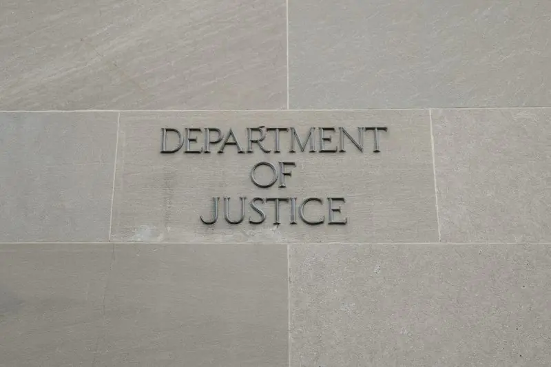 The image shows a sign for the Department of Justice on a stone wall.