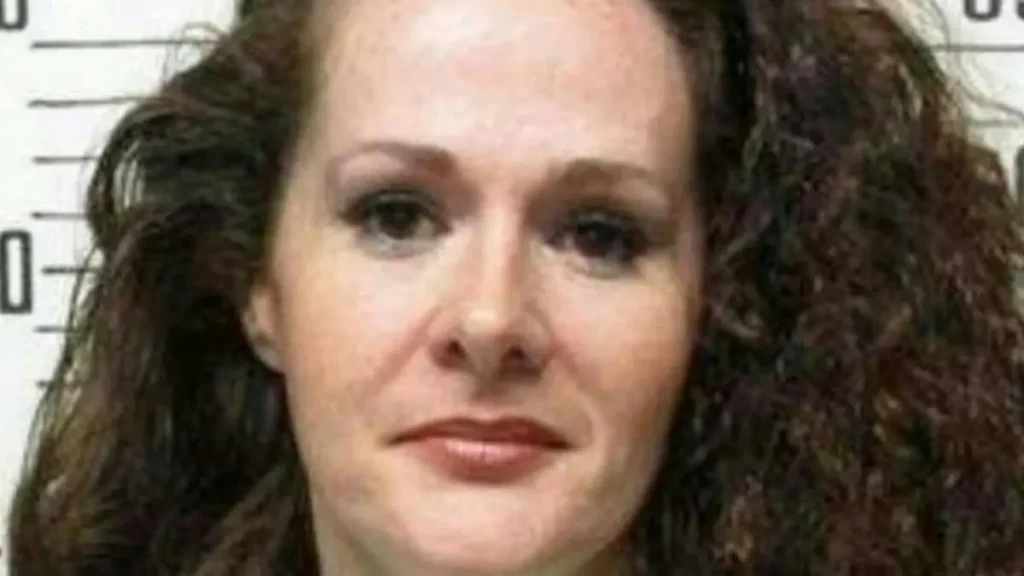 The image appears to be a mugshot of a woman with curly hair.