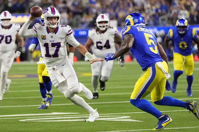 A football player in a white uniform with the number 17 is preparing to throw the ball during a game against a team in blue and yellow uniforms.