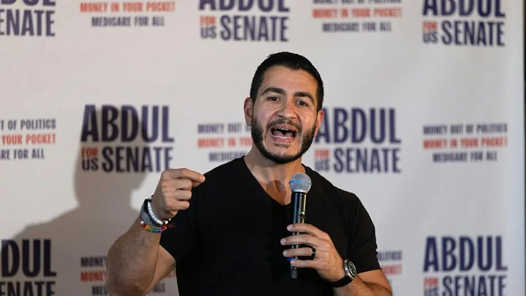 A man is speaking into a microphone at a campaign event for Abdul for US Senate.