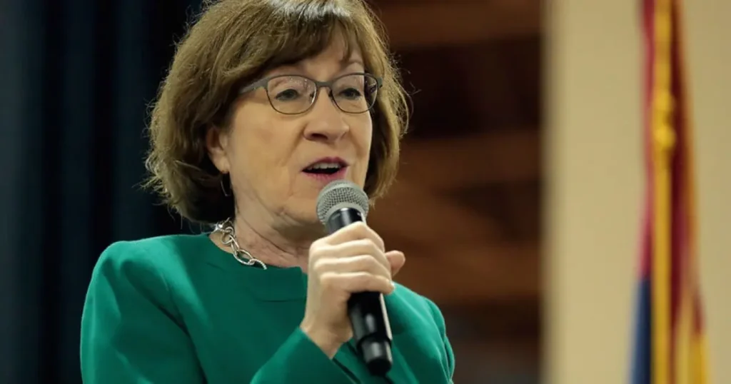 A woman in a green outfit is speaking into a microphone, likely at a formal event or press conference.