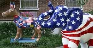 The photo shows two statues, one resembling a donkey and the other an elephant, both painted with American flags, symbolizing political parties.