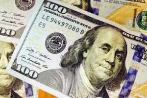 The image shows a close-up of a $100 Federal Reserve Note, featuring Benjamin Franklin's portrait.