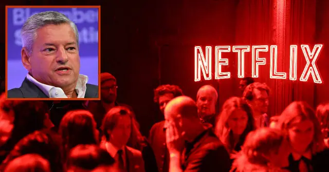 The image shows a man speaking at a Bloomberg event, with a crowd of people in the foreground and a Netflix logo illuminated in the background.