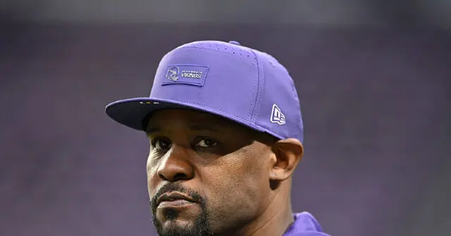 The image shows a person wearing a purple cap with a logo, likely associated with a sports team.