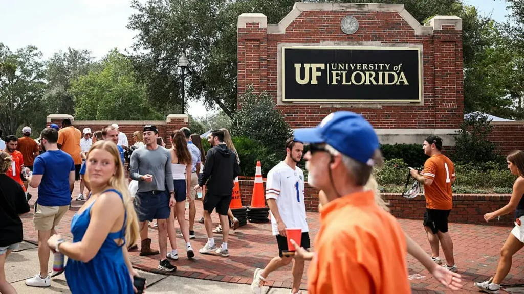The photo captures a lively scene at the University of Florida, with students and visitors gathered near the entrance sign.