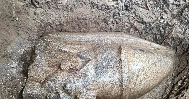 The image shows a stone sarcophagus partially unearthed from the ground, suggesting an archaeological discovery.