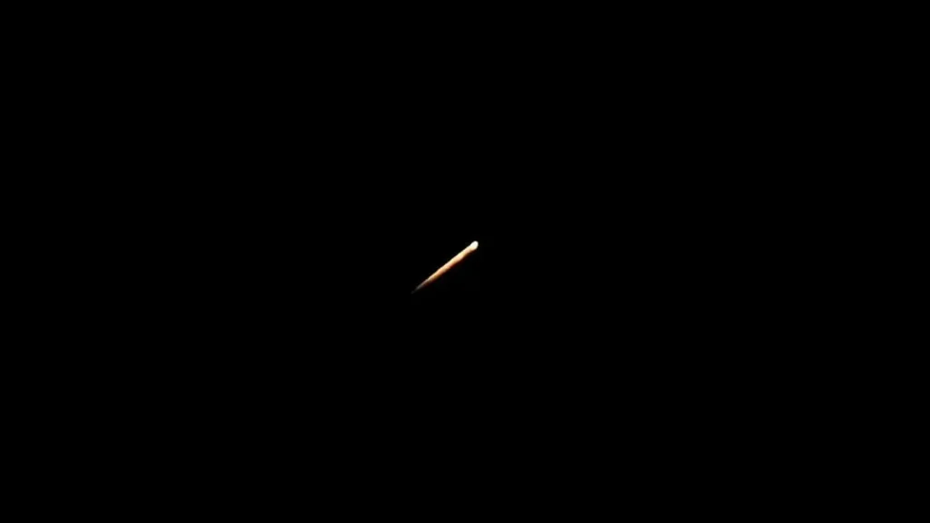 The image shows a single matchstick against a completely black background.