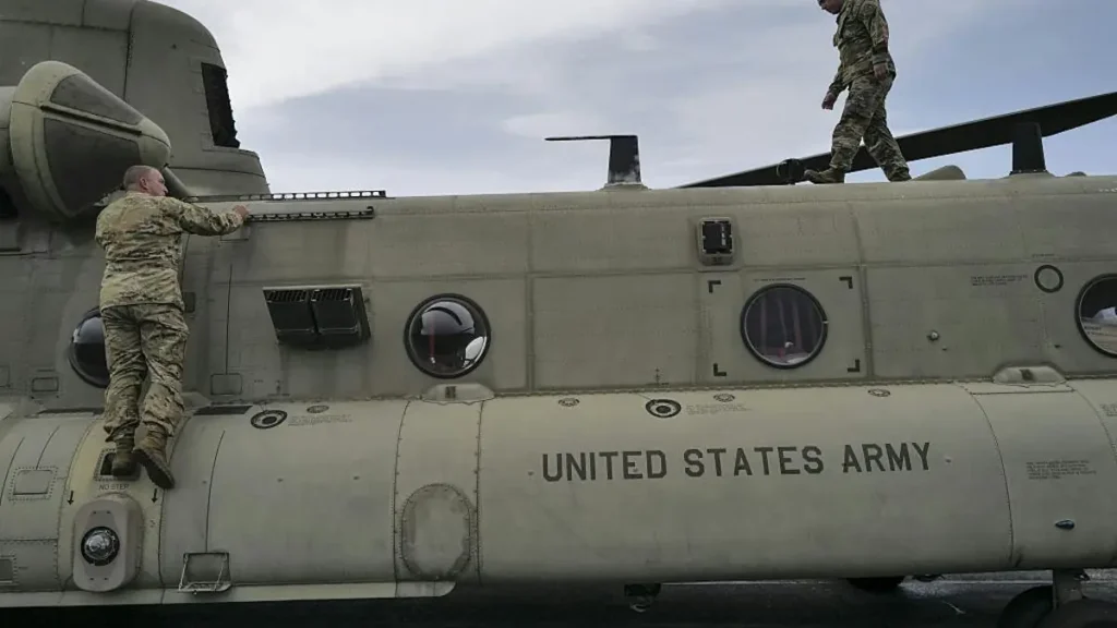 Two soldiers are seen inspecting or preparing a United States Army helicopter.