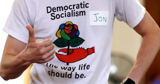 The photo shows a person wearing a shirt that promotes democratic socialism, with the text "The way life should be" and a graphic of a rose and a hammer and sickle.