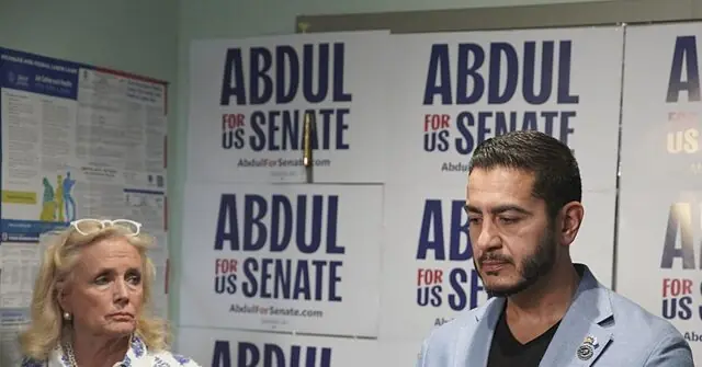 The photo shows a political event with campaign signs for "Abdul for US Senate" in the background.