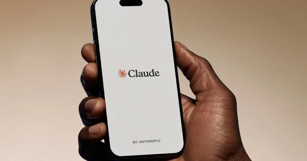 A hand holds a smartphone displaying the "Claude" logo by Anthropic.