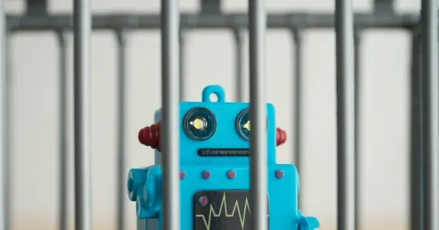A blue toy robot is seen behind a metal fence, creating a sense of confinement or restriction.