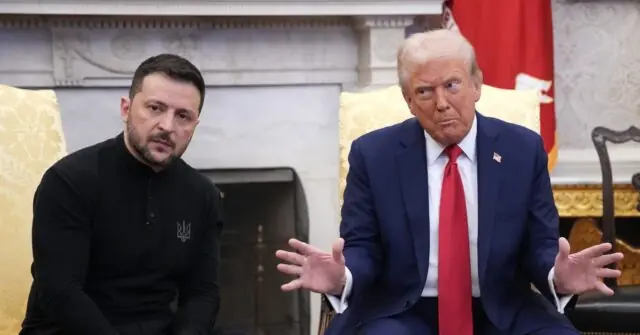 The image shows two individuals seated in a formal setting, with one wearing a black shirt and the other in a suit with a red tie, engaged in a discussion.