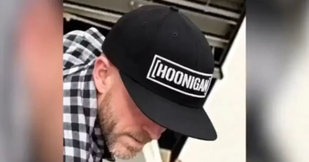 The image shows a person wearing a black cap with the word "HOONIGAN" on it, along with a checkered shirt.