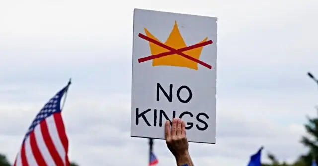 The image shows a protest sign with a crown crossed out and the text "NO KINGS," held up in front of an American flag.