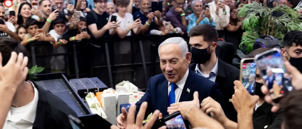 A man in a suit is surrounded by a crowd of people taking photos and videos with their phones.