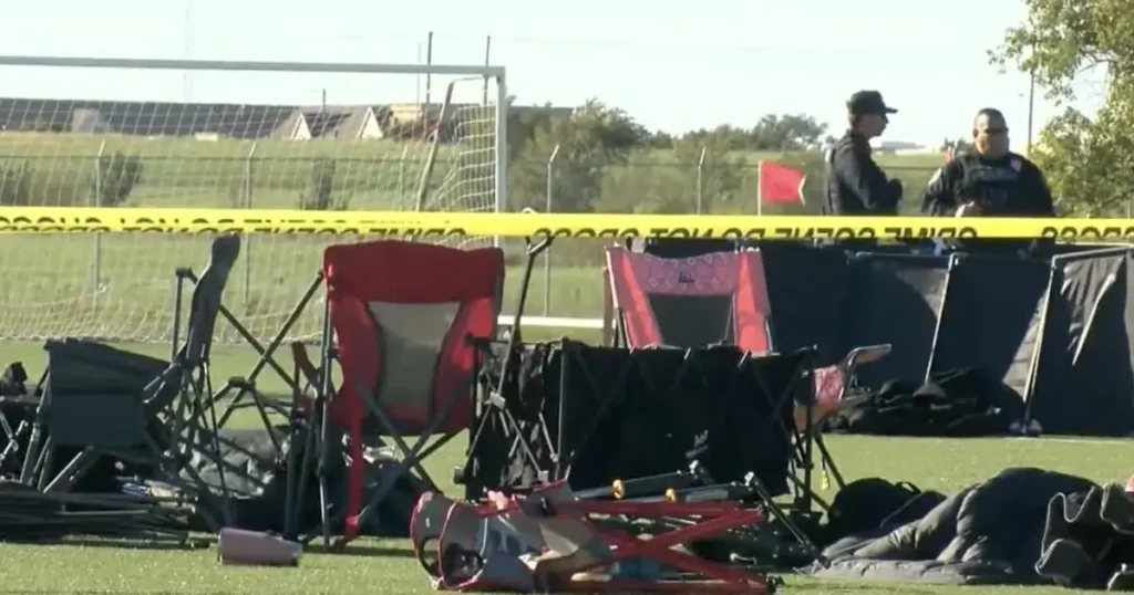 The image shows a crime scene with police tape, camping chairs, and a red flag, indicating an investigation in progress.