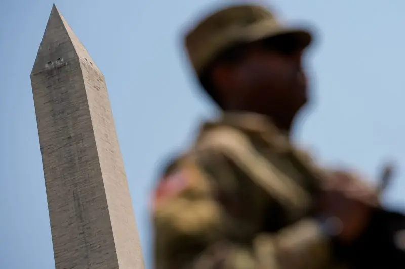 A soldier stands in the foreground with the Washington Monument in the background.