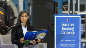 A woman reads a book titled "Margaret and the Moon" during the Summer Reading Challenge event.