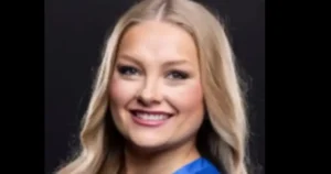 The image shows a person with long blonde hair smiling against a dark background.