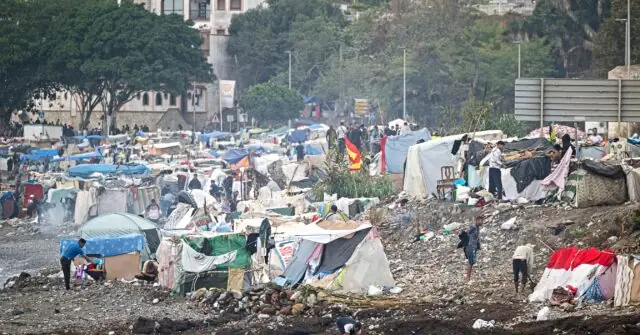 The image depicts a densely packed refugee camp with makeshift shelters and people engaged in various activities.