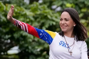 A woman wearing a shirt with the Venezuelan flag and the text "CUM VZLA" waves during a public event.