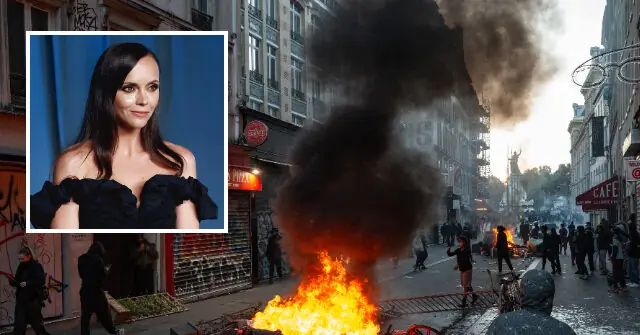 The image juxtaposes a serene portrait of a woman in a black dress with a chaotic street scene featuring a large fire and thick smoke, suggesting a protest or unrest.