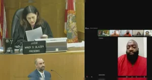 The image depicts a virtual courtroom with Judge Mindy S. Glazer presiding, while a man in a red uniform appears via video call.