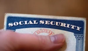 The image shows a close-up of a Social Security card being held by a finger.