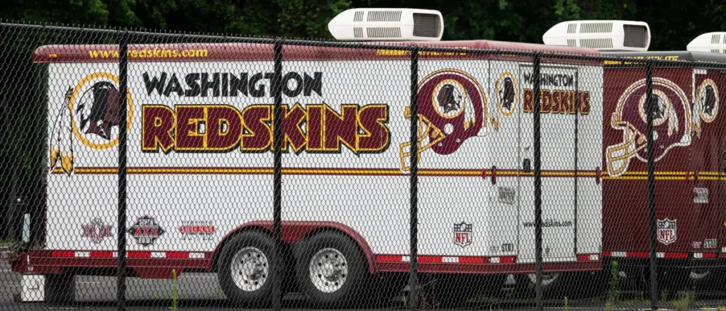A Washington Redskins-branded truck is parked behind a chain-link fence.
