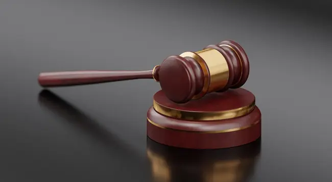 The image depicts a judge's gavel, symbolizing the legal system and the administration of justice.