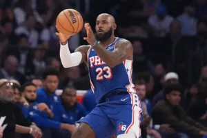 A basketball player in a Philadelphia 76ers uniform is seen dribbling the ball during a game.