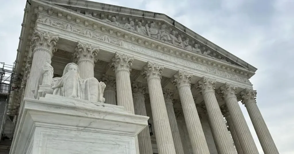 The image shows the exterior of the United States Supreme Court building, featuring its iconic columns and the statue of Justice in front.